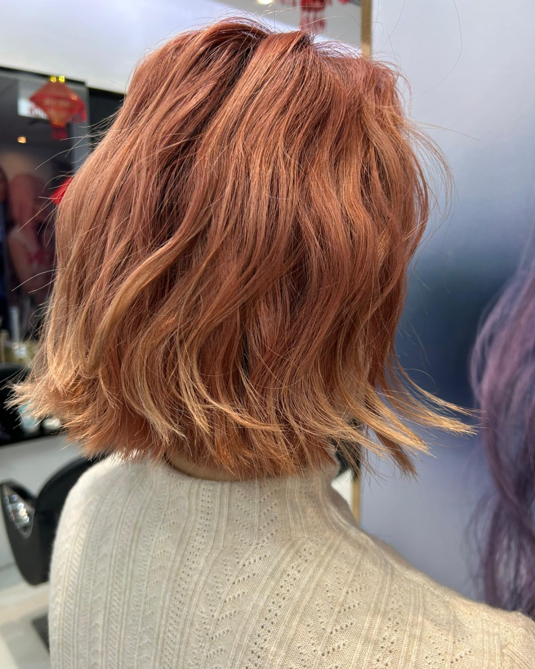 The back profile of a woman's short curly hair coloured in copper brown