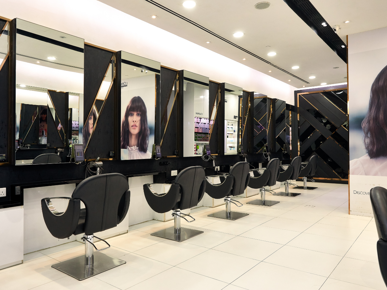 The interior of a hair salon showcasing a row of black chairs facing mirrors.